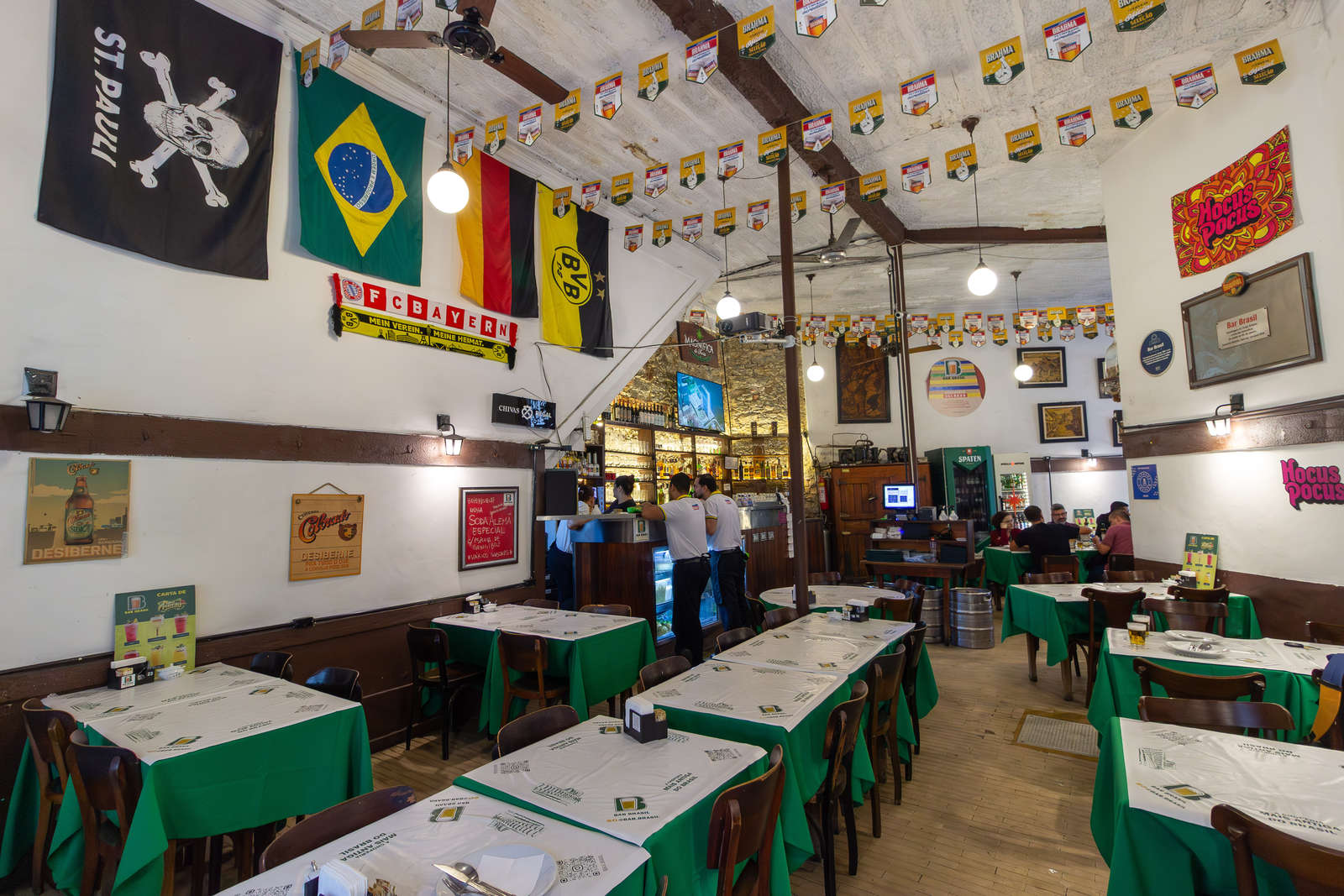 The main dining room at Bar Brasil with flags and green tablecloths