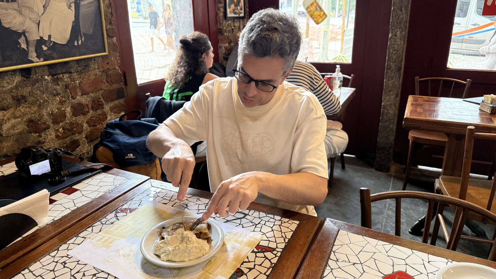 The author cutting apple strudel served with cream at Bar Ernesto