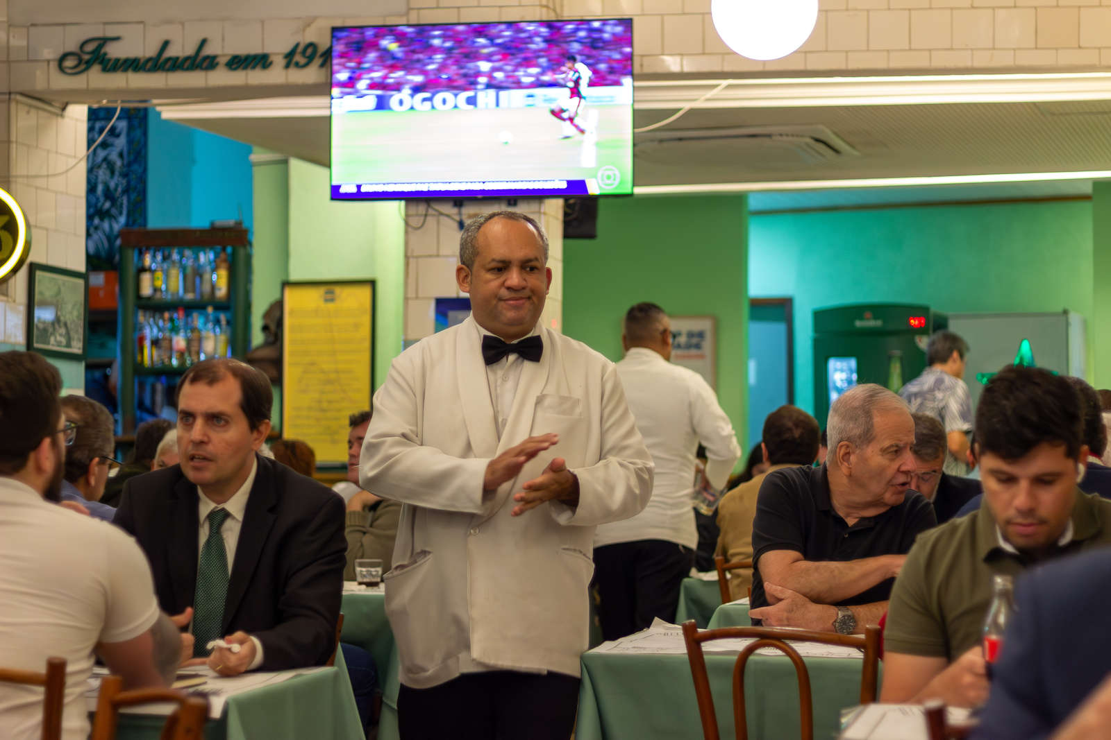 A waiter in a white jacket serving guests at Casa Urich