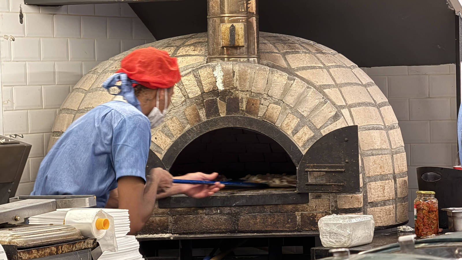 A pizzaiolo preparing pizza in the oven at Zona Sul supermarket
