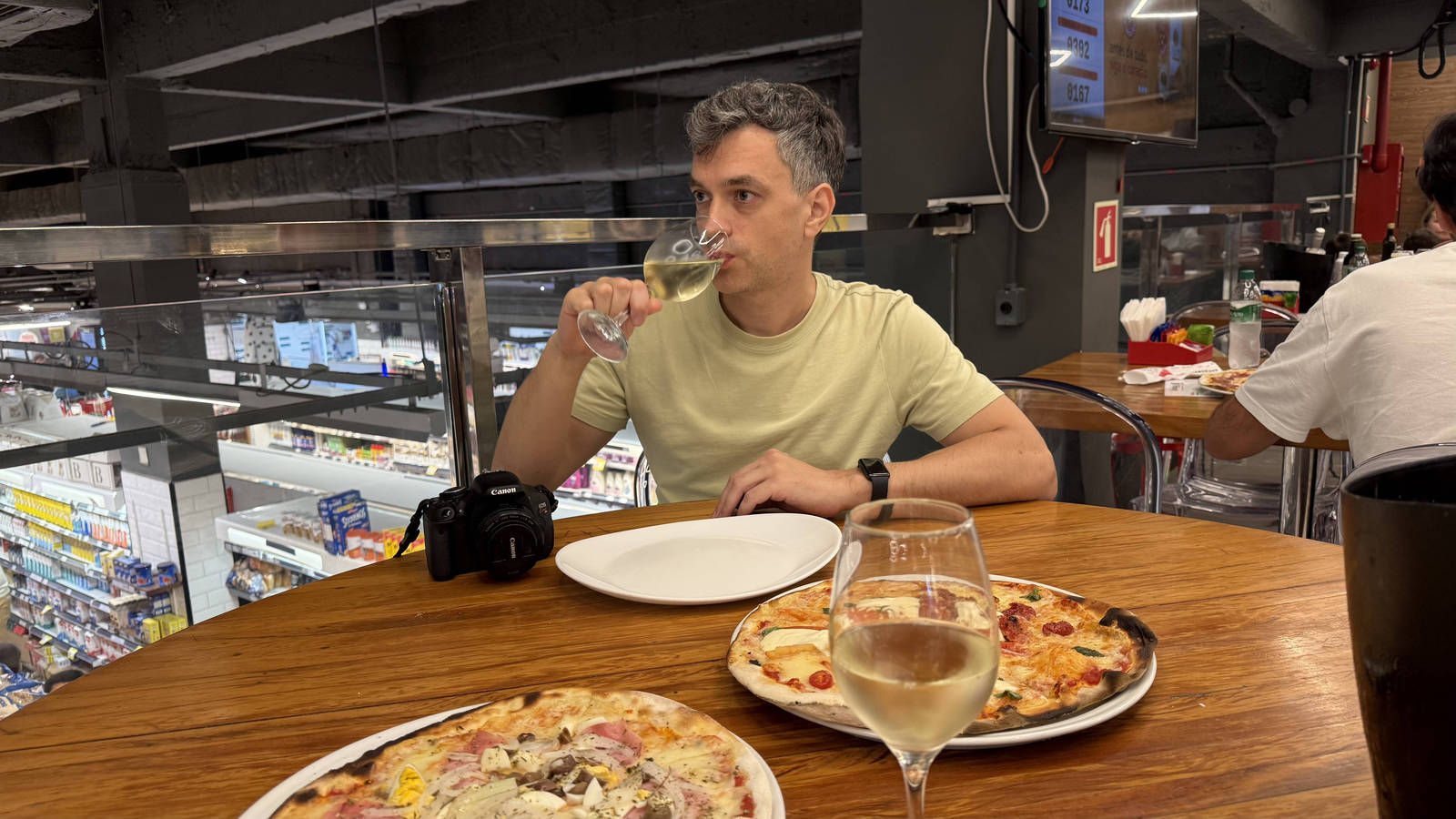 The author trying pizza with white wine at Zona Sul