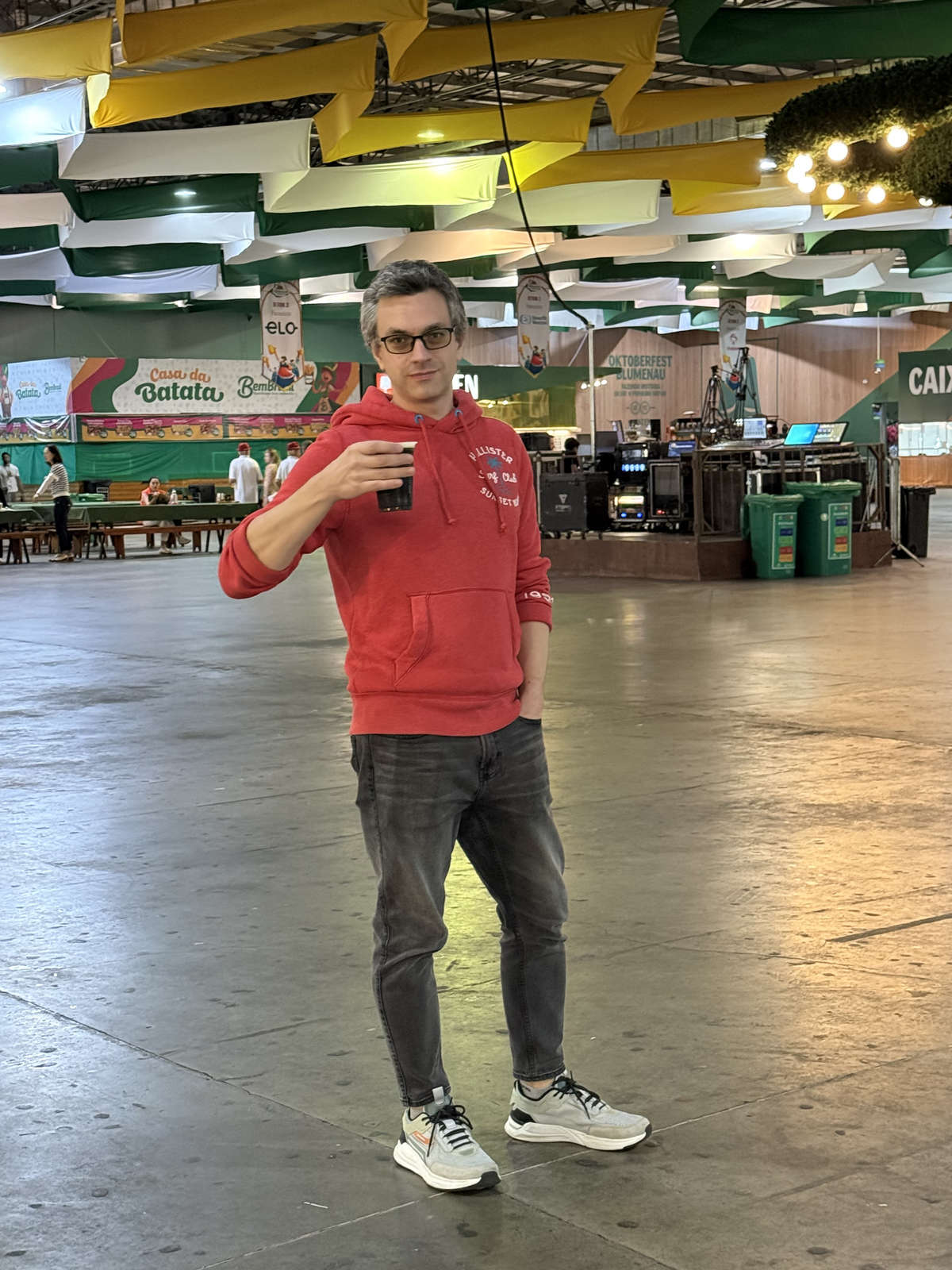A visitor with a drink inside an Oktoberfest Blumenau pavilion