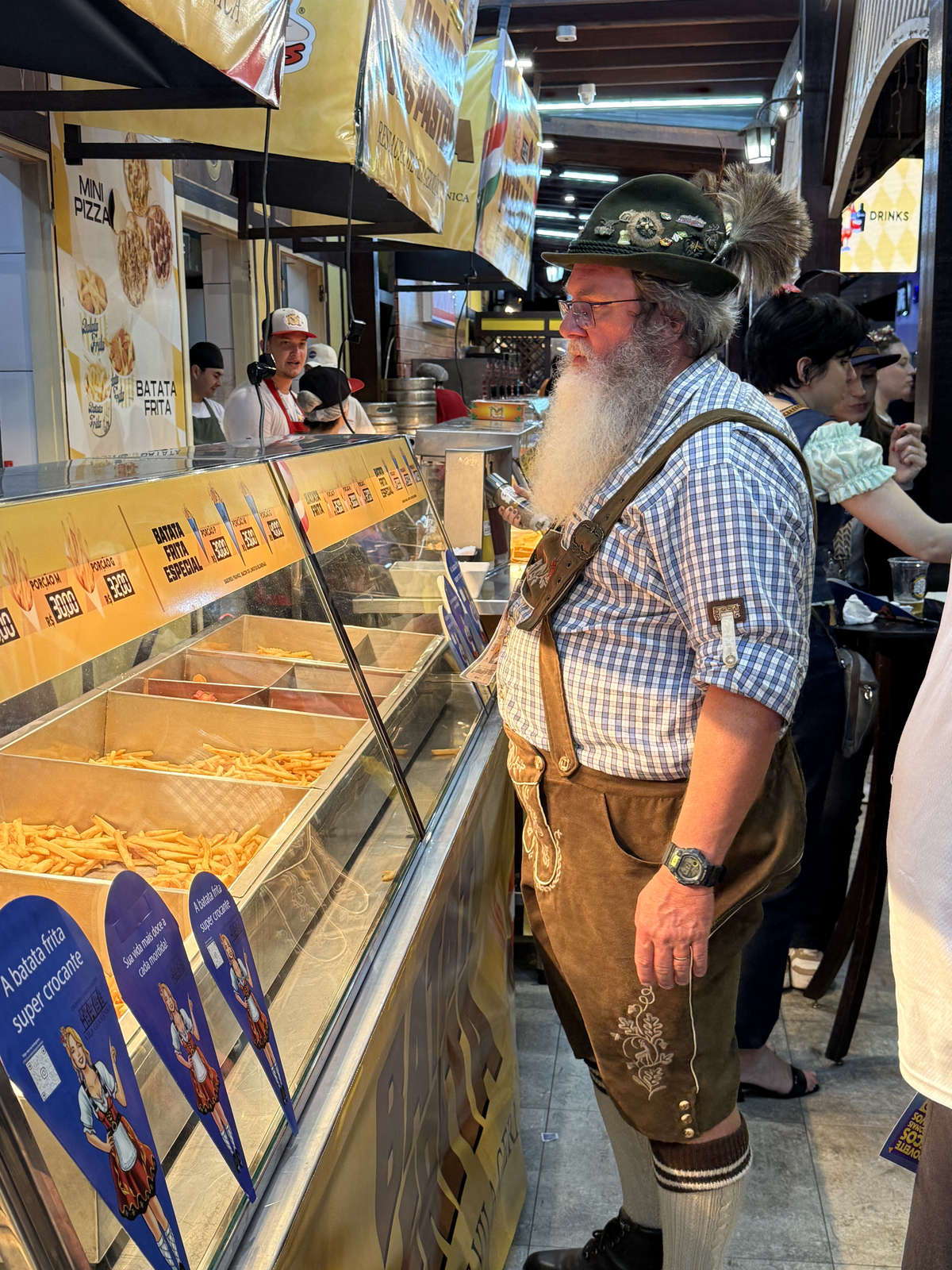 A visitor in lederhosen choosing food at Oktoberfest Blumenau
